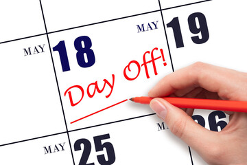 18th day of May. Hand writing text DAY OFF and drawing a line on calendar date 18 May. Vacation...