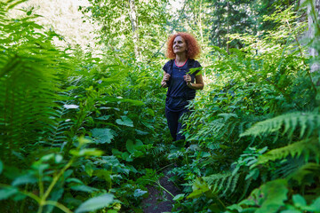 Naklejka na ściany i meble Woman hiking on a trail in the forest
