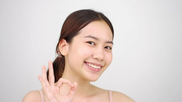 Slow motion of Asian girl beautiful woman face close up looking camera portrait healthy skin natural make up clean beauty fresh skin young female beautiful model.