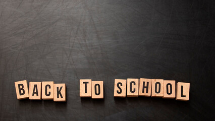 square wooden letters with the phrase "Back To School" written in English on a black chalkboard background