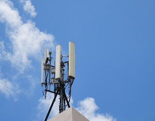 Telecommunication pole of 5G cellular. Macro Base Station. Radio network telecommunication equipment with radio modules and smart antennas mounted on a metal on rooftop against cloulds sky background.