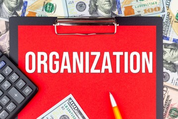 ORGANIZATION - word on the background of money (dollars), a notepad and a pen with a calculator. Business concept (copy space).