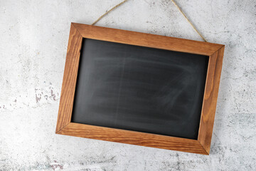 Empty vintage black board or school chalkboard  hanging on stone wall.