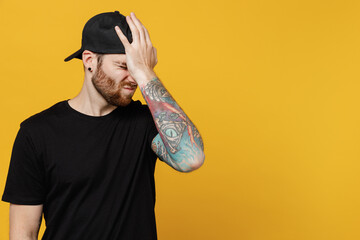 Young bearded tattooed man 20s he wearing casual black t-shirt cap put hand on face facepalm epic...