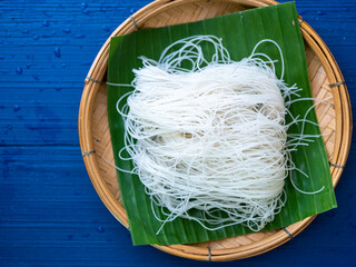 Asian food collection : top view on vermicelli noodles in bamboo basket with navy blue space 