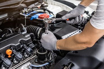 Fototapeta premium Mechanic man working on the engine of the car in the garage.Car service and maintenance,Repair service.Checks car engine under the hood