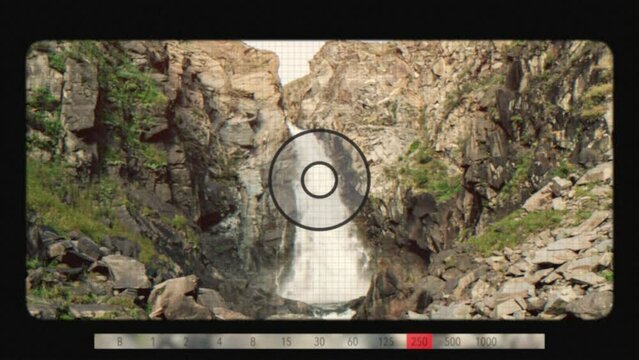 A look through photo camera at waterfall Kurkure in mountains of Altai, Siberia, Russia. Beautiful summer nature landscape at during daytime