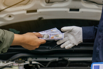 Mechanic man takes cash as payment from customer.after finish checking car system.Professional...