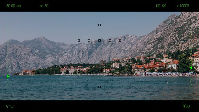 A look through photo camera at bay of Kotor with old town in Montenegro. Summer landscape with mountain and clear blue sky