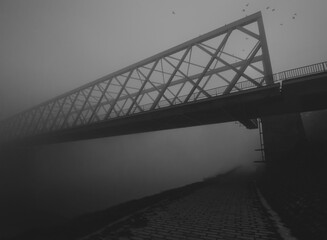 Silhouette of the bridge over river on misty autumn day