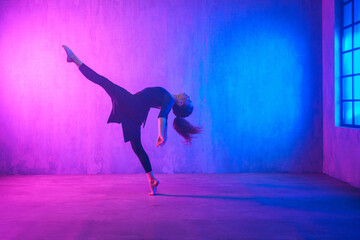 Modern dance girl dancer dancing in neon light doing gymnastic exercises in studio, copy space.