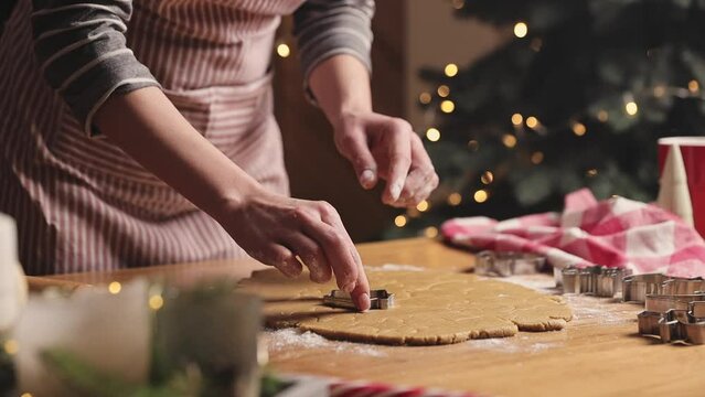 Merry Christmas, Happy New Year. Gingerbread cookies cooking, baking. Young woman sculpts, cuts and carves gingerbread cookie figures from kneaded dough using different various special kitchen forms