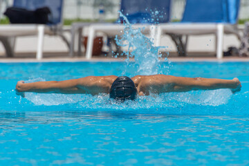 Close up action shot of athlete, young man, teenager swimming butterfly style. Sport, recreation concept.