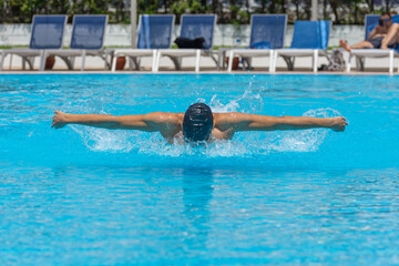 Close up action shot of athlete, young man, teenager swimming butterfly style. Sport, recreation concept.