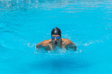 Fototapeta na wymiar Close up action shot of athlete, young man, teenager swimming butterfly style. Sport, recreation concept.