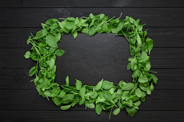 Kitchen table with stone cutting board, decorated with herbs. Presented on the black wooden background with center empty space. Table top view.