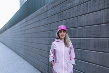 Young woman in fashion clothes standing in city concrete wall.