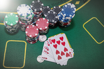 poker chips with playing cards on green casino table.
