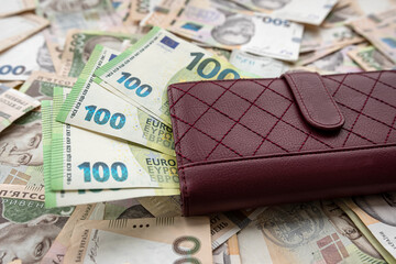 leather puse full in euro banknotes lying on ukraine money uah hryvnia, exchange concept.