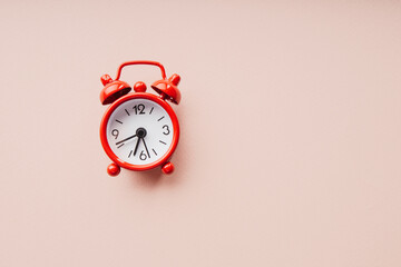 Red alarm clock isolated on a pink paper background