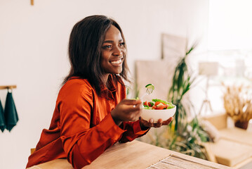 Beautiful young woman eating salad in the kitchen in the morning. Healthy food. Close up. Portrait...