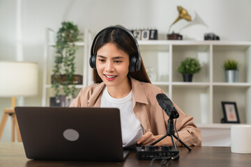 Cheerful beautiful Asian woman in a white t-shirt with wearing headphones and using laptop at video...