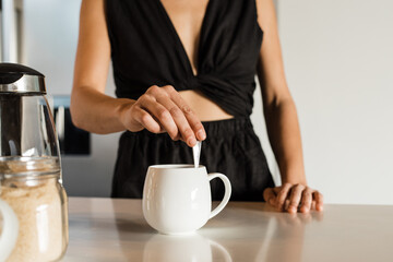Midsection of woman making coffee on kitchen island