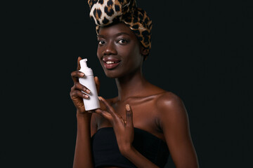 Smiling black girl hold bottle with cosmetic cream