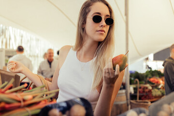 Blond woman wearing sunglasses buying pear in market