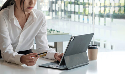 Young Asian businesswoman enjoy shopping online using credit card at a coffee shop.