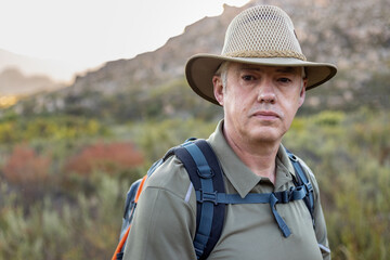 Fototapeta premium Portrait of male traveler wearing hat hiking at countryside