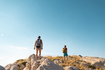 Obraz premium two girls with backpacks walk along a mountain path.
