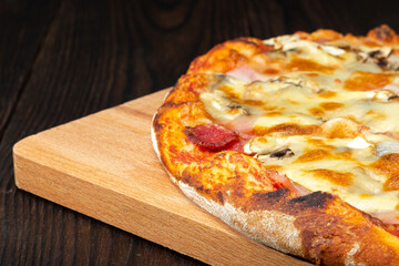 pizza on a cutting board on a dark wood table
