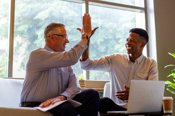 Male partners giving high five while celebrating growth