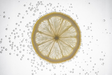 Fresh lemon slice in water with bubbles on white background