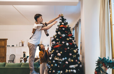 Girl clap while man put star on christmas tree
