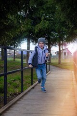 Life style close-up portrait red-haired boy 6-7 years old runs along a wooden bridge in the park cheerful childhood, vacation holidays, spring