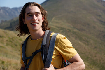 Thoughtful man with long hair hiking on mountain at sunset