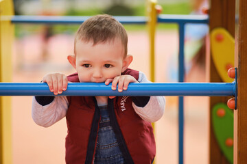 Fototapeta na wymiar Sad toddler baby boy on the playground, unhappy child aged one year