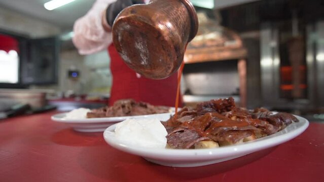 Turkey Iskender kebab. 
Pouring sauce on meat.
