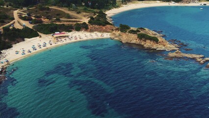 Obraz premium Some tourists relaxing on quiet sandy beach of Sarti. Greek summer holidays. Aerial view. Shallow turquoise sea water. High quality photo