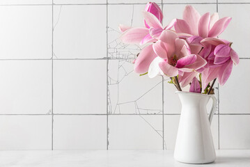 Pink magnolia flowers in vase on white tile background. womans day or wedding background with copy space