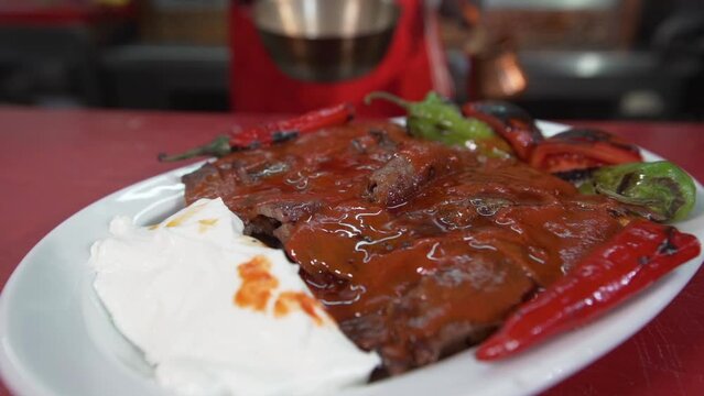 Turkey Iskender kebab. 
Pouring sauce on meat. Butter sauce.
