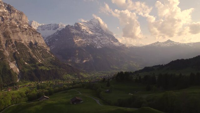 Aerial drone footage raising up revealing moody views of picturesque mountain village in front of eiger north face