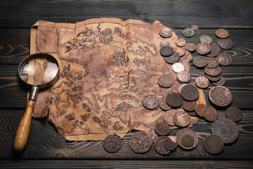 Metal detector, ancient coins and old treasure map on the table top view background. Treasure hunting concept.