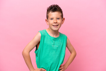 Little caucasian boy isolated on pink background posing with arms at hip and smiling