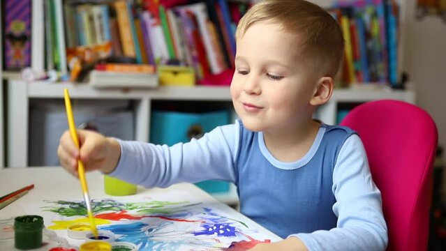 Portrait of cute little blond kid boy enjoy have fun painting with watercolor and brush bright abstract inage on paper at home or kindergarten class. Imagination development children play activity