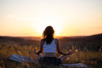 woman meditating outdoors at sunset