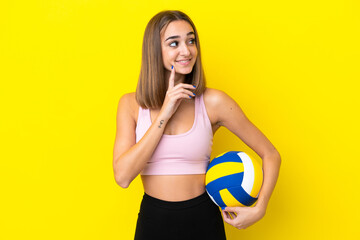 Young woman playing volleyball isolated on yellow background thinking an idea while looking up