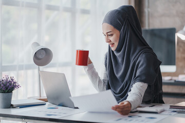 happy muslim business women in hijab at work smiling arab woman taking notes and work on laptop